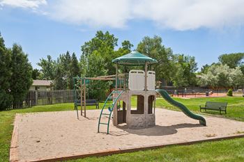 A playground with a green slide and a wooden structure